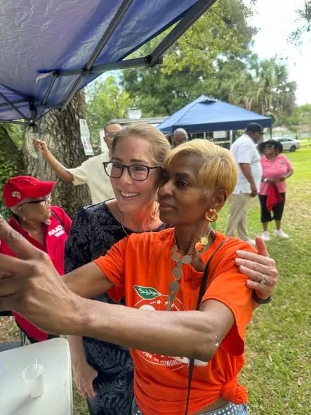 David Jolly embraces a woman in an orange shirt at an outdoor community event